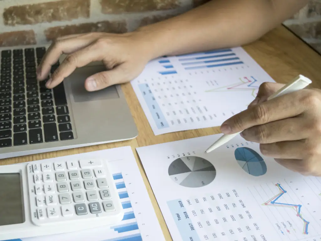 Accountant Performing Calculations Analyzing data charts on laptop and paper